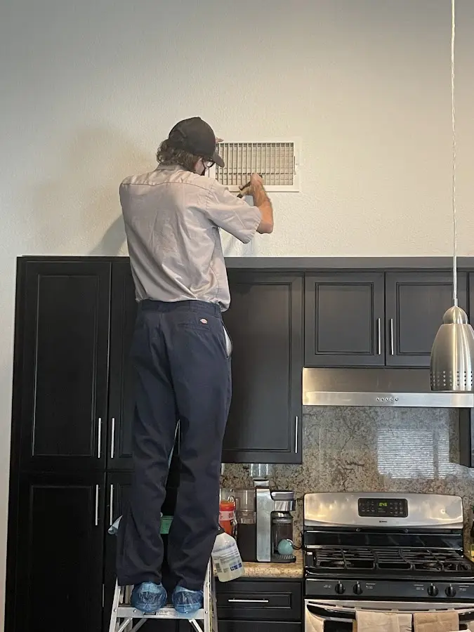 Technician inspecting an air vent during HVAC service in Sand Lake
